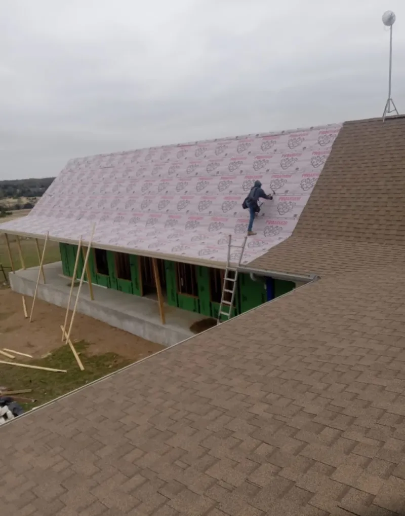Worker preparing underlayment for a metal roof installation in Kennett Square